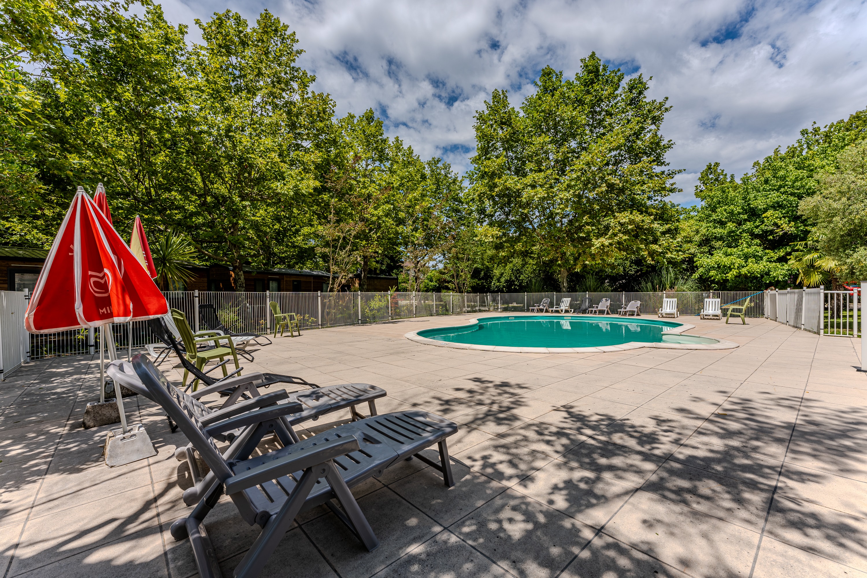 Piscine avec parasols rouges au camping L'Orée des Landes